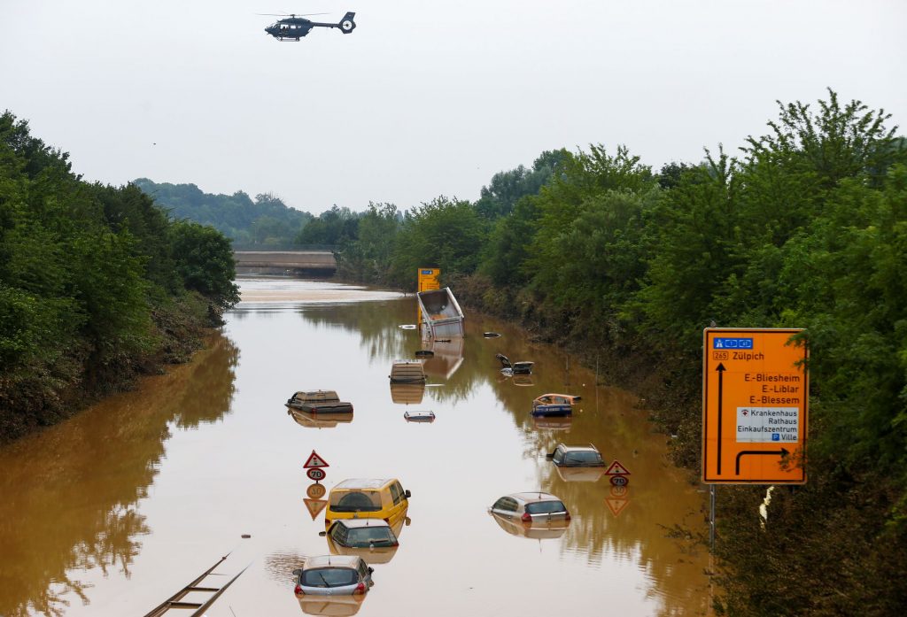 A helicopter flies above cars partially submerged in floodwaters on the road following heavy rainfalls in Erftstadt-Blessem, Germany, July 17, 2021. REUTERS/Thilo Schmuelgen